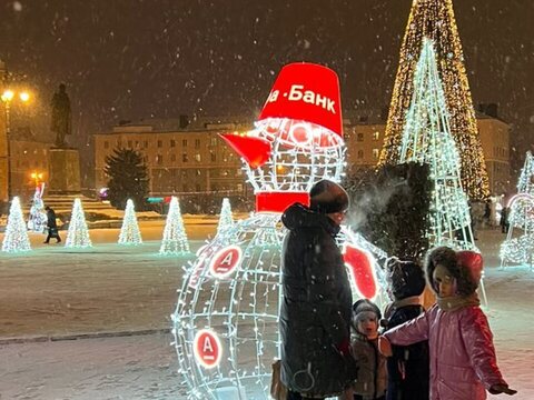 Световая фигура снеговика на заснеженной городской площади